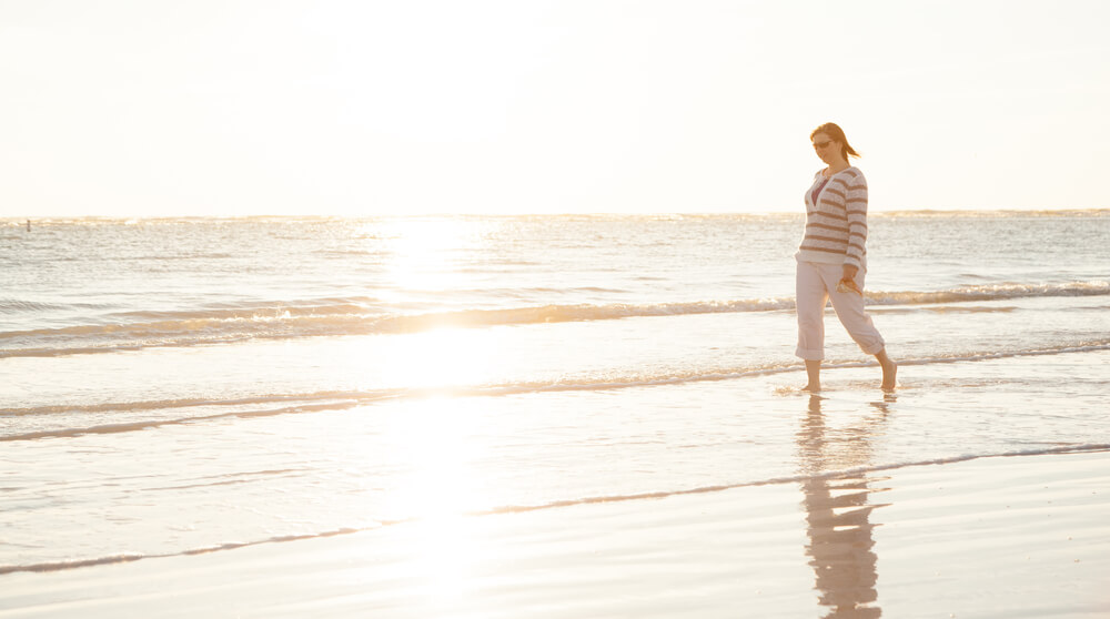 A woman walking on the beach on a fall vacation in Gulfport, Florida.